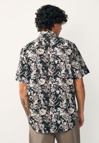 Trumpomis rankovėmis marškiniai su gėlių raštu juodos, kremo ir smėlio spalvų. Pagaminti iš lengvos medžiagos, su laisvo kirpimo dizainu.