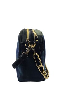 Sac à main en daim bleu foncé avec deux zips dorés, une bandoulière en cuir noir et un détail en chaîne dorée, vu de côté.