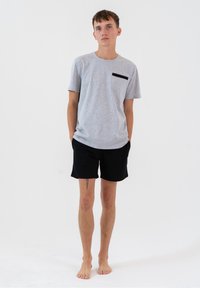 Szary t-shirt z czarną kieszenią, w połączeniu z czarnymi szortami. T-shirt ma krótkie rękawy i swobodny krój, a oba elementy wykonane są z miękkiego materiału.