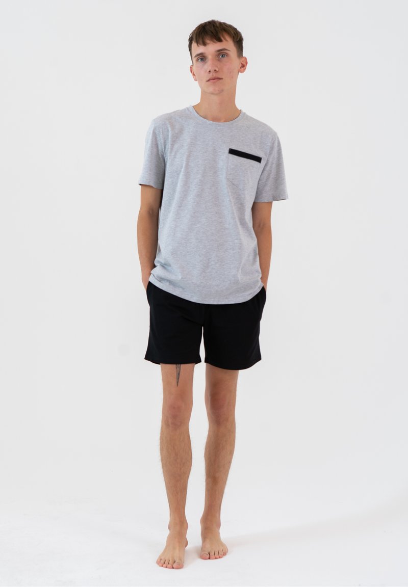 Szary t-shirt z czarną kieszenią, w połączeniu z czarnymi szortami. T-shirt ma krótkie rękawy i swobodny krój, a oba elementy wykonane są z miękkiego materiału.