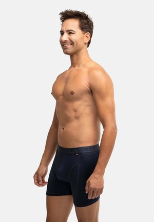 Pantaloni boxer blu navy con una cintura morbida, realizzati in materiale flessibile, presentano un design aderente e dettagli di cucitura sottili.