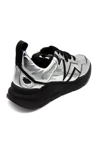 Silberne, metallische Sneaker mit einem schlanken Design, schwarzen Akzenten, strukturierten Sohlen und einem gepolsterten Kragen für zusätzlichen Komfort.