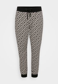 Joggers en negro y beige con un patrón, que cuentan con una cintura con cordón y puños elásticos, presentando un intrincado diseño geométrico en toda su superficie.