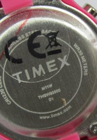 Boîtier de montre en acier inoxydable avec un bracelet en silicone rose. Détails gravés comprenant "TIMEX", le numéro de modèle et une étanchéité de 30 mètres.
