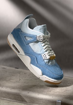 Zapatilla de denim con acentos en azul claro y blanco. Cuenta con una malla transpirable, un collar acolchado y un detalle de herraje dorado en la lengüeta.