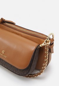 Lille brun og mørkt mønstret læderhåndtaske med gyldent lynlås, kæderem og Michael Kors-logo på frontklappen.