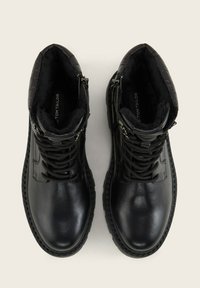Stivali alla caviglia in pelle nera con colletto texture, design con stringhe e cerniere laterali. Presentano una punta rotonda e suola in gomma per una migliore aderenza.