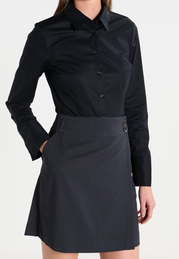 Svart skjorta med knappar och långa ärmar, kombinerad med en mörkgrå kjol med figurnära midja och två accentknappar.