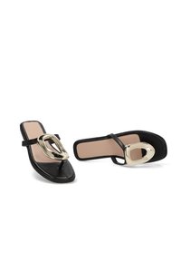 Sandalias de tira negra con punta cuadrada, con plantillas beige y grandes hebillas decorativas de tono dorado brillante en las correas.