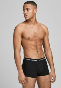 Boxer-briefs noirs pour hommes avec une ceinture élastique blanche arborant la marque "JACK & JONES". Le tissu semble lisse et ajusté.