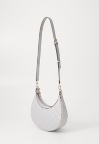 Hvid quilted skuldertaske med justerbar rem og hardware i guldtonet, vist hængende mod en ensfarvet baggrund.