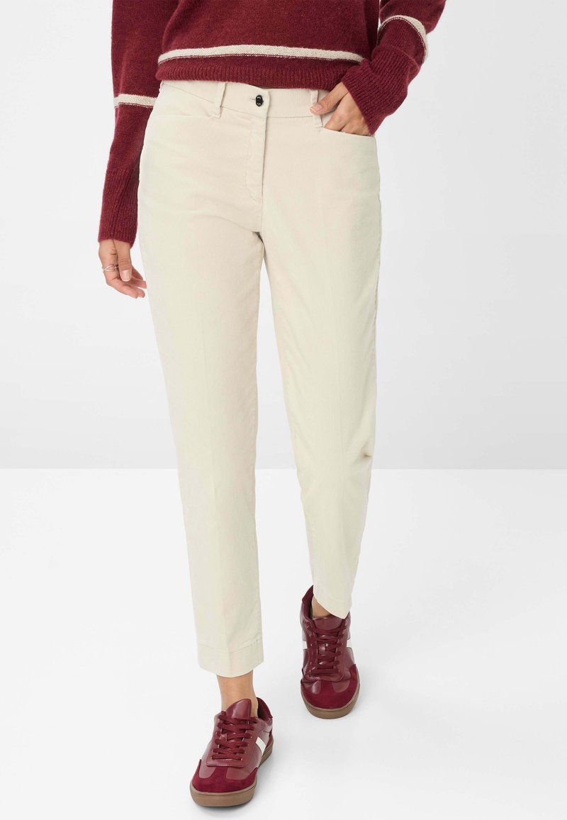 Beige kordfløjspants med slim fit, der har forlommer og knaplukning, parret med bordeaux sneakers.