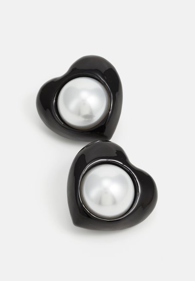 Boucles d'oreilles en forme de cœur noir avec une finition lisse, chacune présentant une perle blanche brillante en son centre, créant un contraste audacieux de couleurs.