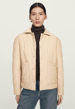 Beige gesteppte Jacke mit einem Kragen, Druckknöpfen, zwei Vorderentaschen und geripptem Muster an den Bündchen.