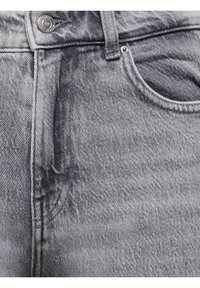 Gros plan sur un jean en denim gris montrant la poche avant, la passoire de ceinture et le détail du bouton en métal.