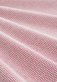 Rózsaszín és fehér textúrájú anyag, kis, rácsszerű mintával. Puha, szőtt anyag, sima hullámokban omlik.