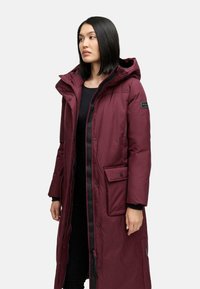 Lang maroon pufferjakke med hætte, knaplukning foran, sidelommer og kontrasterende sort hardware. Glat tekstur og knælangt design.