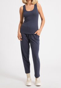 Débardeur marine avec un col rond, associé à un pantalon tapered assorti avec une taille élastique. Des baskets blanches à plateforme complètent le look.