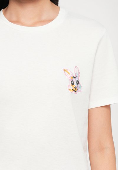 White cotton t-shirt featuring a colorful embroidered cartoon bunny on the left chest area, with pink, yellow, and black detailing.