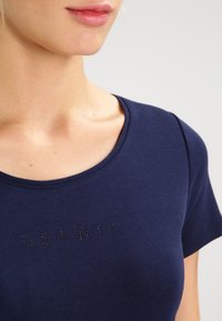 Námořnická modrá tričko vyrobené z měkké, elastické látky s kulatým výstřihem a krátkými rukávy. Obsahuje logo "ESPRIT" z černých kamínků.