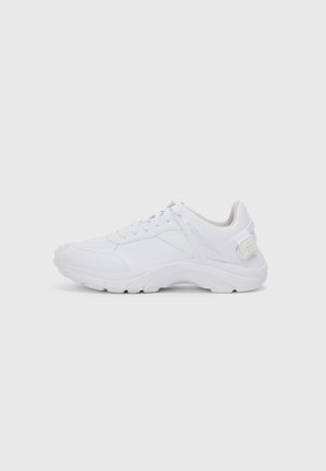 White athletic shoes featuring a smooth synthetic upper, cushioned sole, rounded toe, and branded heel accent. Laced design for secure fit.
