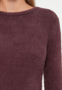 Lila, flauschiger Pullover mit geripptem Muster und weitem Rundhalsausschnitt. Weiches Material sieht warm und leicht aus. Lange Ärmel mit minimaler Verzierung.