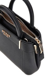 Piccola borsa nera realizzata in pelle sintetica texturizzata con hardware dorato, doppi manici e chiusura con zip caratterizzata da un logo distintivo.