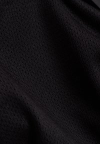 Svart texturerat tyg med ett fint, geometriskt mönster. Mjukt, något elastiskt material som faller smidigt.