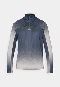 Langermet treningsgenser med halvlukket krage, gradient farge fra marineblå til lys grå, glatt stoff og et emblem på brystet.