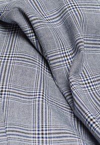 Gewebter Stoff in einem blauen und weißen Karomuster mit feinen Linien und unterschiedlichen Texturen, der ein weiches, atmungsaktives Textil zeigt.
