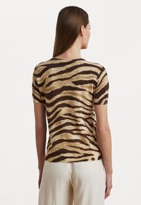 T-shirt de manga curta em malha com um padrão de riscas de tigre em castanho e bege. Textura suave com decote redondo e silhueta ajustada.