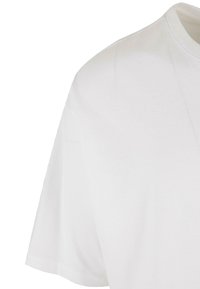Hvid bomulds t-shirt med rund halsudskæring, korte ærmer og glat tekstur. Sømdetaljer synlige på skulderen.
