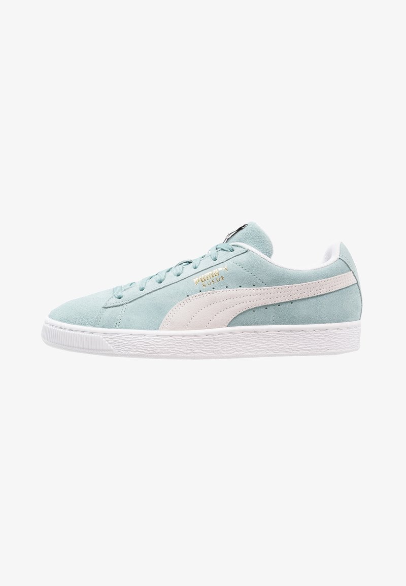 Baskets en daim bleu clair avec semelle blanche, bande latérale Puma blanche, lacets bleu clair et logo doré "Puma Suede" sur le côté.