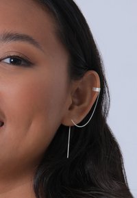 Pendiente de oreja de plata que presenta una banda horizontal texturizada y una cadena larga y delgada que se desliza sin esfuerzo a lo largo del lóbulo de la oreja. Acabado suave.
