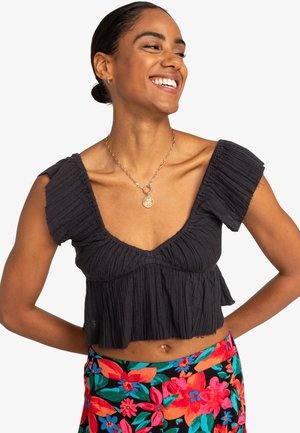 Čierny plisovaný crop top s hlbokým výstrihom do V a krátkymi rukávmi. Skombinovaný s farebnou kvetinovou vzorovanou sukňou s vysokým pásom.