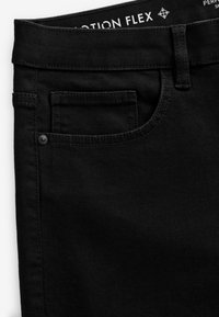 Schwarze Jeanshose mit glatter Textur, ausgestattet mit einer Fronttasche, dezenten Nähten und einem Knopfdetail am Bund.