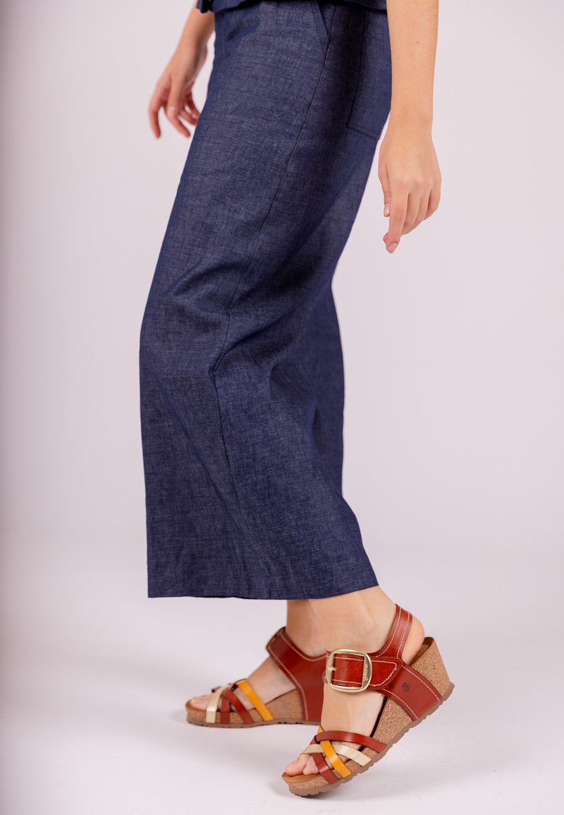 Denim wijde broek in donkerblauw met een subtiele textuur en zijzakken, gecombineerd met bruingele strap sandalen met een sleehak.
