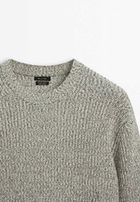 Pull en maille épaisse gris clair avec col rond côtelé et coutures texturées visibles.
