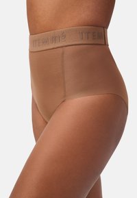 Culotte a vita alta senza cuciture in tessuto marrone chiaro, con una morbida cintura elastica con logo "ITEM m6" in rilievo. Texture liscia su tutta la superficie.