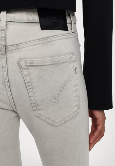 Jasnoszare dżinsy z charakterystyczną tylną kieszenią z ozdobnym przeszyciem oraz czarną skórzaną metką na pasku.