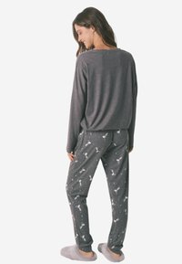 Grijze lange mouw top met een losse pasvorm, gecombineerd met grijze pyjamabroek met een witte dierenprint. Zachte textuur, casual ontwerp en een ontspannen vorm.