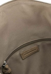 Sacca in tessuto marrone con un interno testurizzato, dotata di chiusura con zip e un'etichetta che recita "FRED & BRUDER." Materiale liscio e resistente.