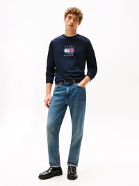 Mornarski srajc z dolgimi rokavi z grafiko "TOMMY HILFIGER", v kombinaciji s svetlo modrimi ravnimi hlačami in črnimi loaferji. Preprost, sproščen videz.