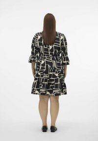 Robe à motifs noir et crème avec des volants superposés, des manches trois-quarts et une ceinture à nouer, conçue pour un ajustement décontracté.