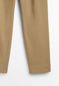 Pantalons en coton beige avec une coupe droite, présentant des lignes épurées, une texture lisse et un ourlet replié.