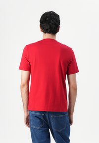 Rode katoenen t-shirt met een klassieke ronde hals en korte mouwen, gecombineerd met blauwe denim jeans met standaard achterzakken.
