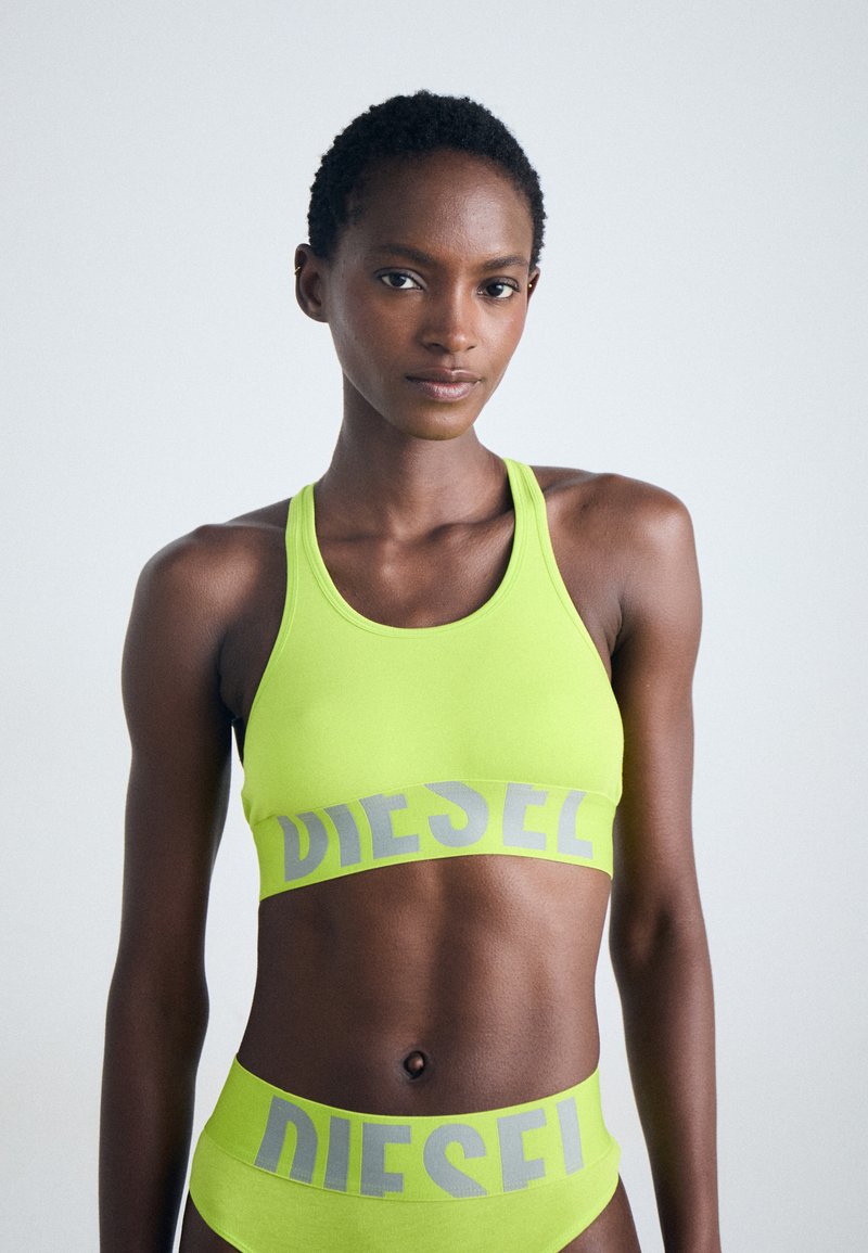 Νεο άσπρο αθλητικό σουτιέν και αντίστοιχο εσώρουχο σε κίτρινο νέον με γκρι λογότυπο "DIESEL" στην ελαστική ζώνη; λείο, ελαστικό ύφασμα; αθλητικός σχεδιασμός.
