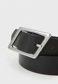 Cinturón de cuero negro con una hebilla rectangular de plata con un acabado liso, cinco agujeros de ajuste y una superficie texturizada.