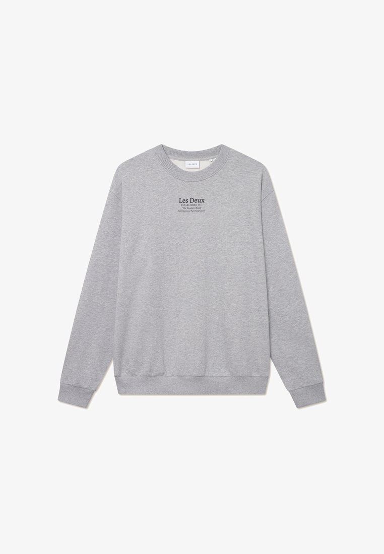 Pelēka kapuce ar apaļu kakla izgriezumu, garām piedurknēm un ribotām aprocēm. Priekšpusē ir melns drukāts uzraksts. Izgatavota no mīksta kokvilnas maisījuma.