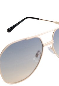 Occhiali da sole in metallo dorato con lenti sfumate grigie, dotati di naselli trasparenti e un'asta nera con la scritta "MADE IN CHINA" in bianco.